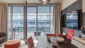 Ett modernt hotellrum med en matplats, en soffa och ett stort fönster med utsikt över staden.