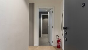 En hall med en brandsläckare, en dörr med lås och en lampa i taket.