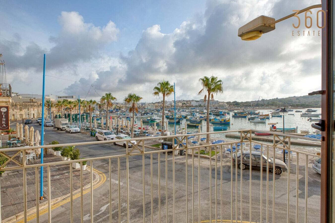 Marina con barcos, calle con automóviles y edificio con un letrero.
