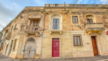 A historic building with a red door, arched windows, and a balcony.