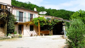 A rustic building with a covered porch, a wooden bench, and a gravel driveway. - Métairie de Lamourade (Saint-Ferriol)
