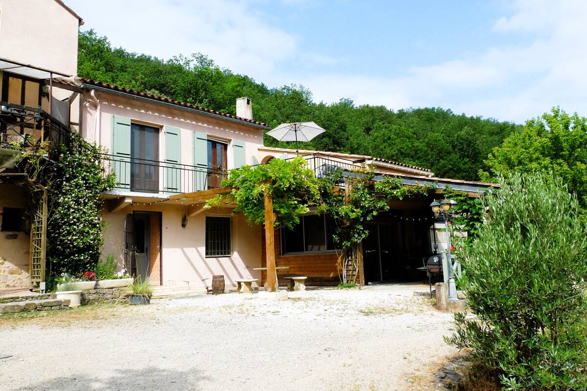 A rustic building with a covered porch, a wooden bench, and a gravel driveway.