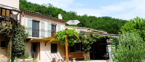 A rustic building with a covered porch, a wooden bench, and a gravel driveway.