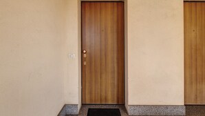 Eine Holztür mit Schlüsselloch und Schloss in einer beige gefärbten Wand mit strukturierter Oberfläche.