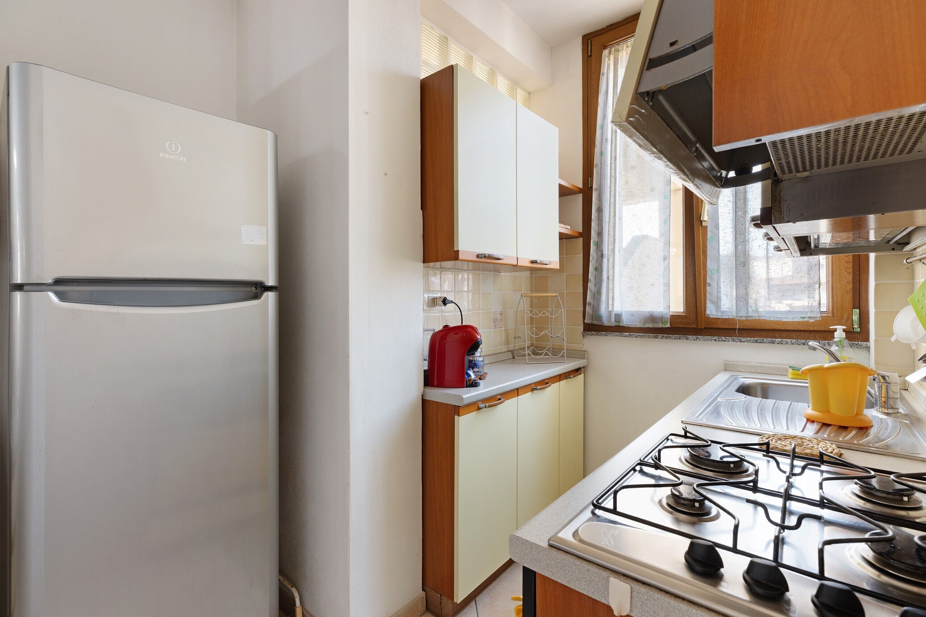 Une cuisine équipée d’un réfrigérateur, de placards, d’une cuisinière et d’une fenêtre.