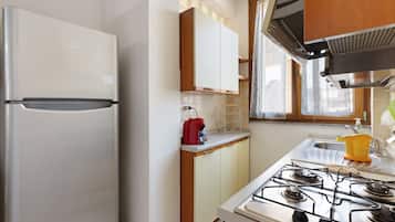 Une cuisine équipée d’un réfrigérateur, de placards, d’une cuisinière et d’une fenêtre.