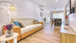 A modern living room with a sofa, a dining area, and a kitchen counter. - Qala Tranquil Escape - Stylish with Terrace & AC (Qala)