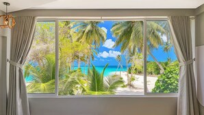 A bedroom with a large window offering a view of a beach and palm trees. - WhiteSand (Himandhoo)