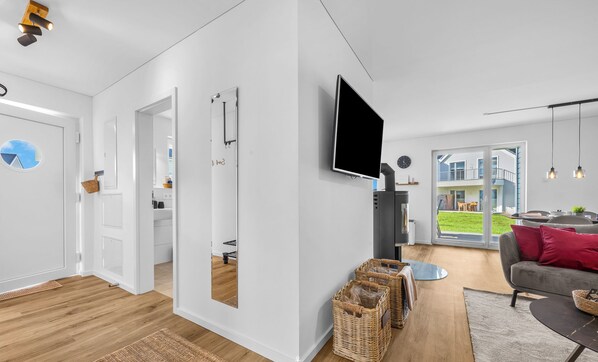 A modern living room with a flat-screen TV, wicker baskets, and a grey sofa.