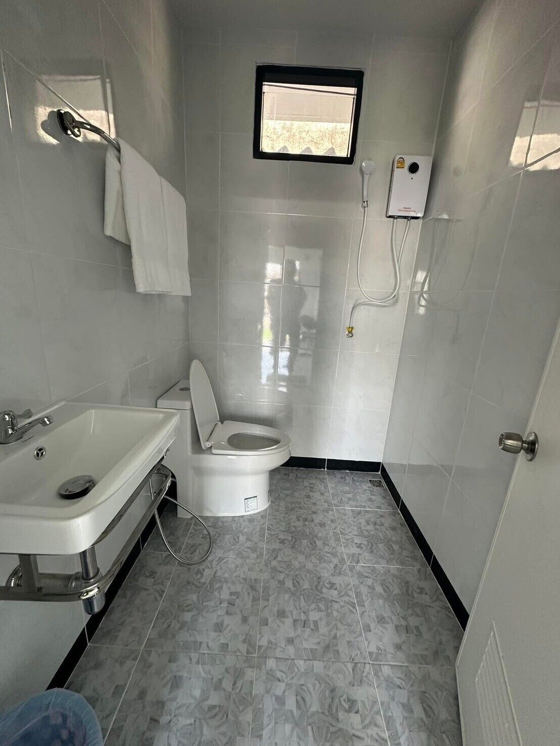 A compact bathroom with a toilet, sink, and a small window.