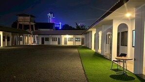 A courtyard with a paved area and artificial grass, surrounded by white buildings with arched windows and doors. - 17 Garden  (Pattaya)