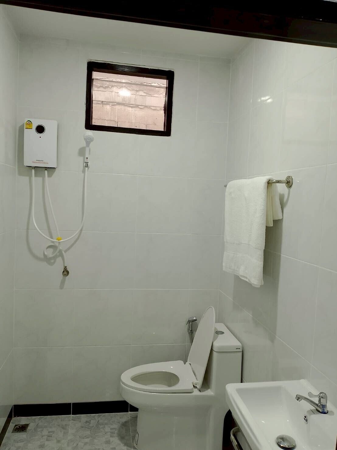 A small, clean bathroom with a toilet, sink, and shower.