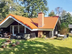 A house with a sloped roof, a chimney, and a covered porch with outdoor furniture. - 4 Star Holiday Home in Silkeborg (Silkeborg)