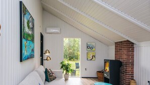 Ein gemütliches Wohnzimmer mit einer Couch, einem Tisch, einem Kamin und einem Bild an der Wand.