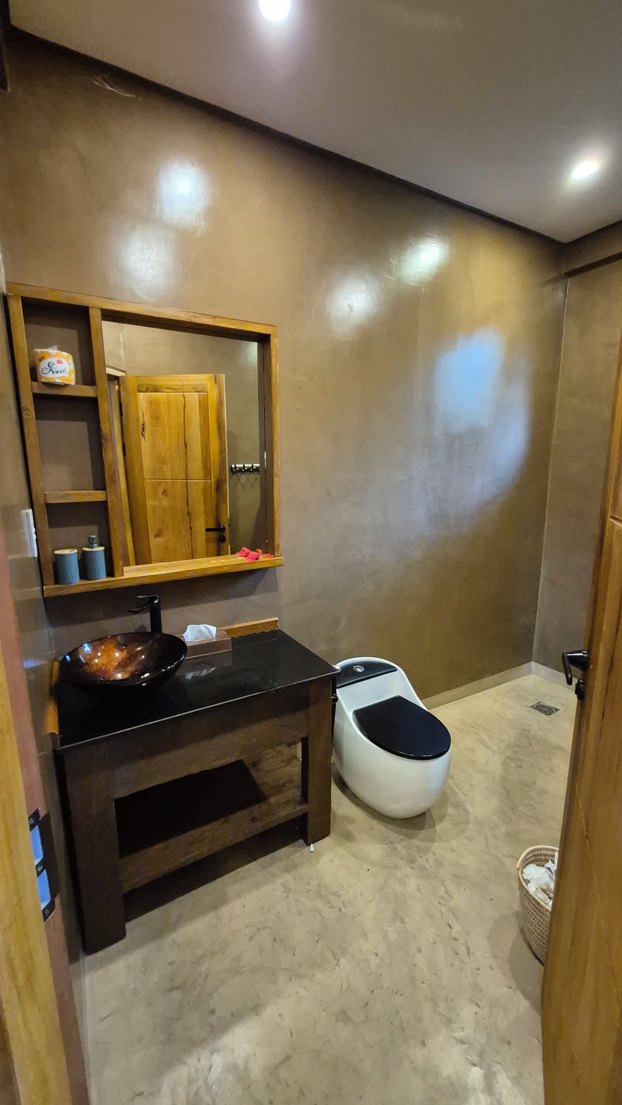 Une salle de bain avec un meuble-lavabo en bois, un évier, des toilettes et un miroir.