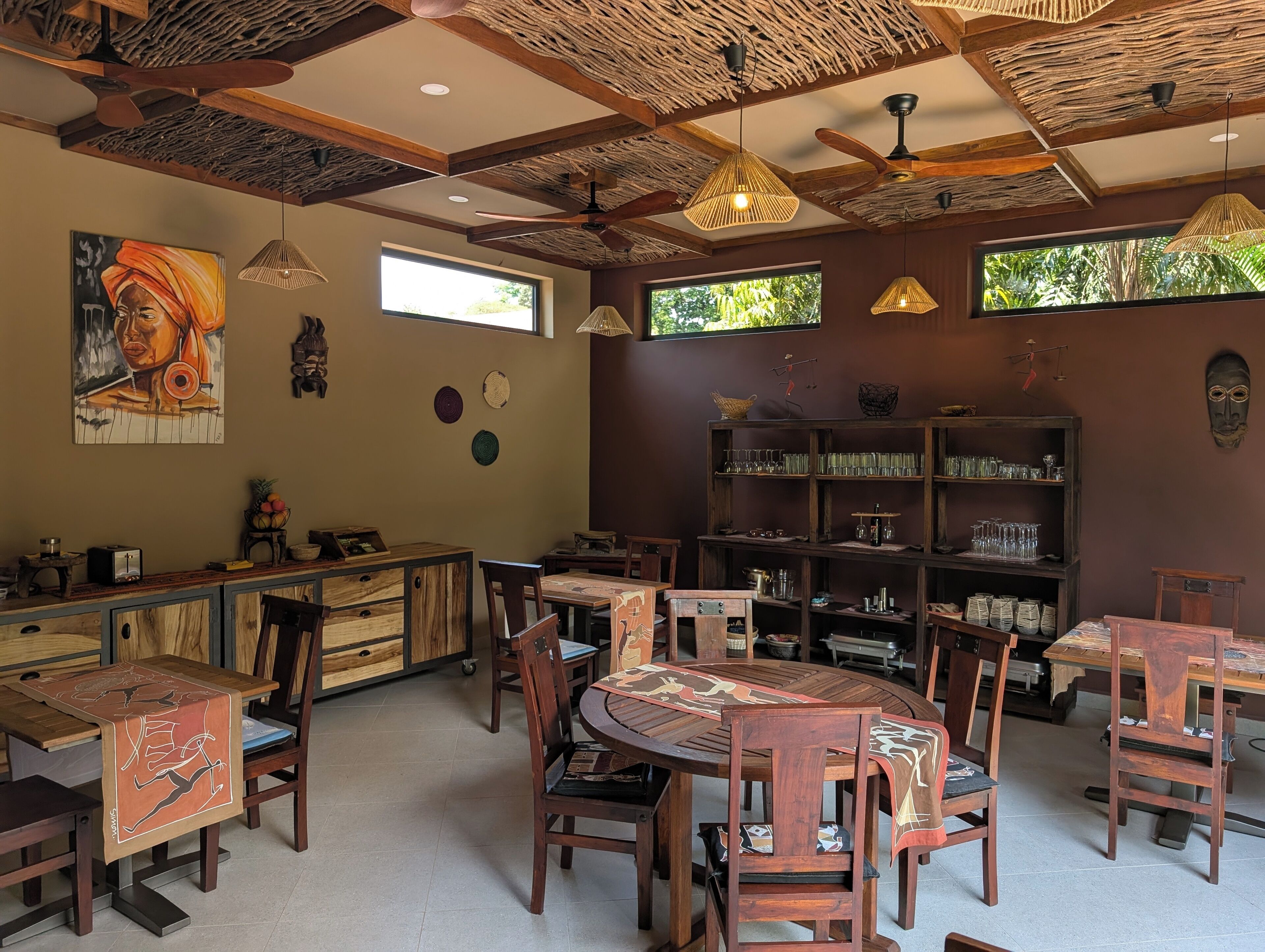 A restaurant with wooden furniture, woven ceiling, and artwork on the walls.