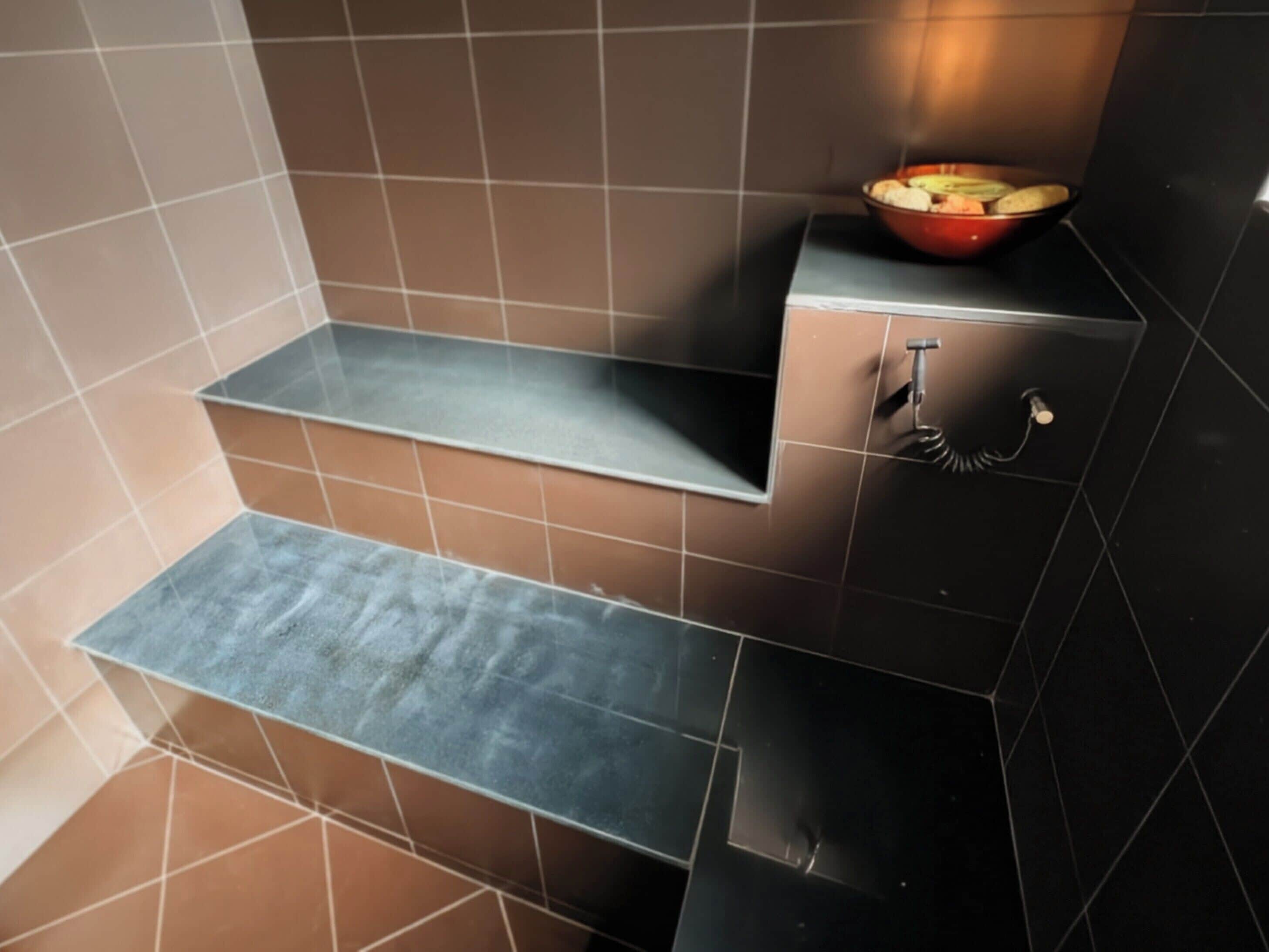 A bathroom with a modern design, featuring a built-in shelf and a towel rack.