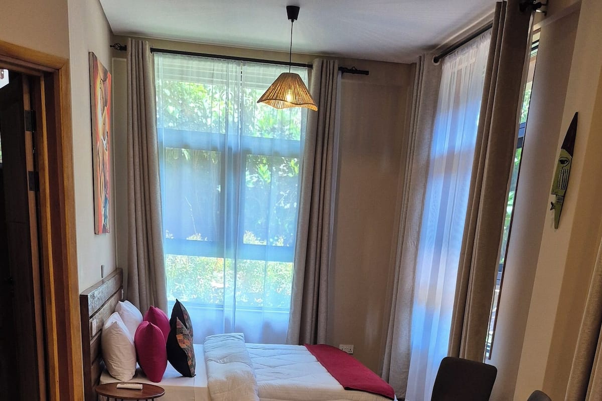 A hotel room with two beds, a wooden floor, a dining table, and a chair.