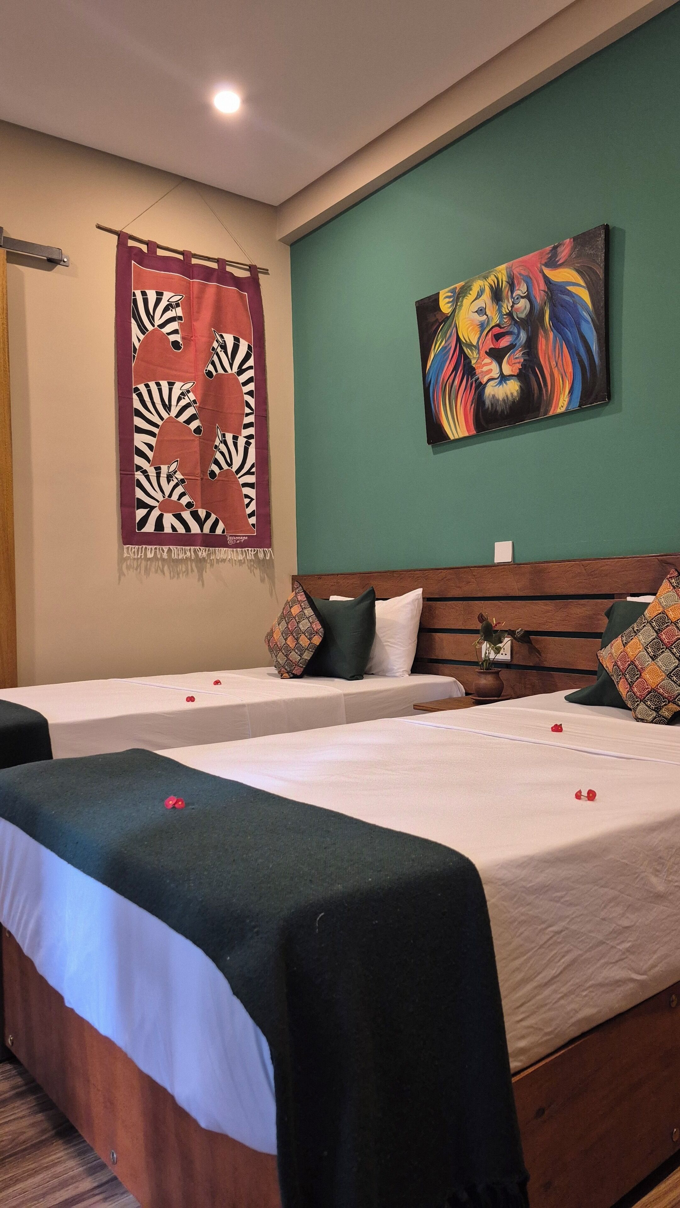 A hotel room with two beds, a green wall, and a painting of a lion.