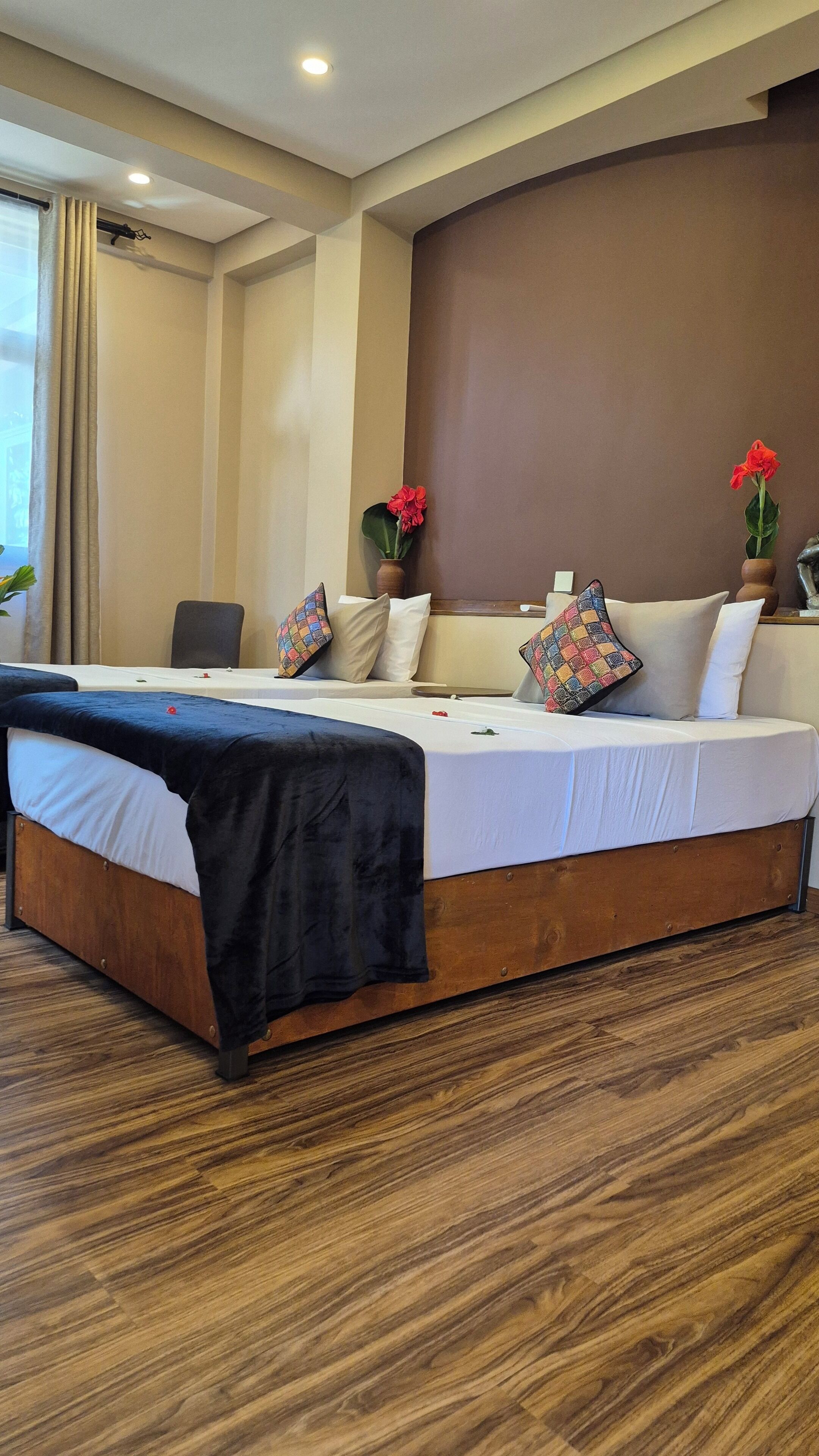 A modern hotel room with a large bed, wooden flooring, and a view of the outdoors.
