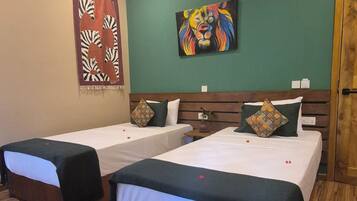 A hotel room with two single beds, a wooden headboard, a green accent wall, and a zebra-themed curtain.