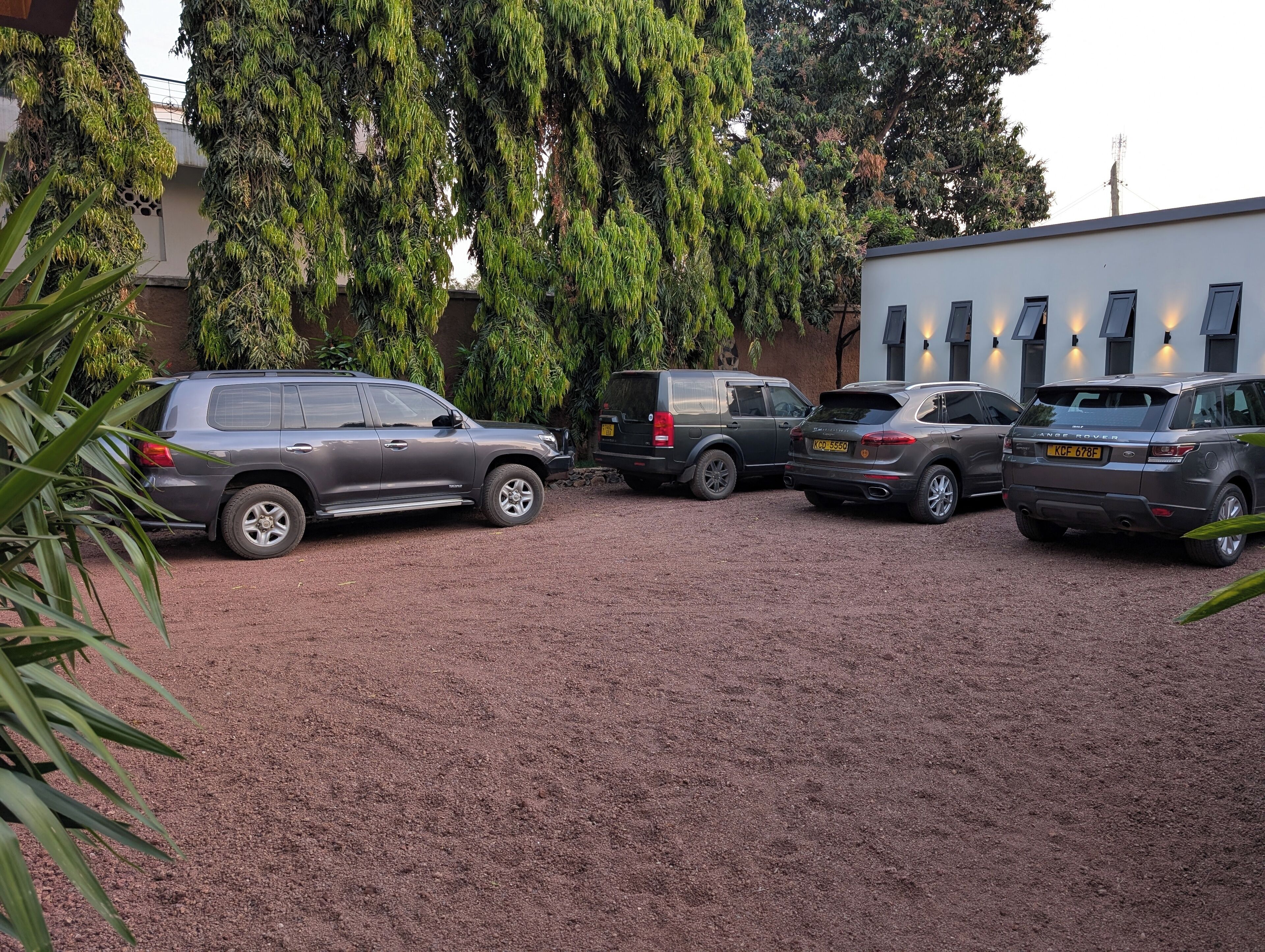 A gravel driveway with four SUVs parked.