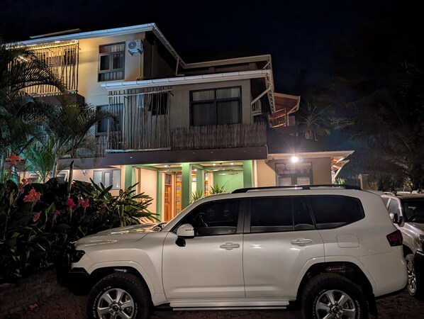 A two-story house with a balcony, a car parked in front, and a well-lit entrance. - Explorers Kilimanjaro Boutique Hotel (Moshi)