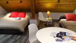 Ein gemütliches Zimmer mit zwei Betten, einem kleinen Tisch und einer Lampe.