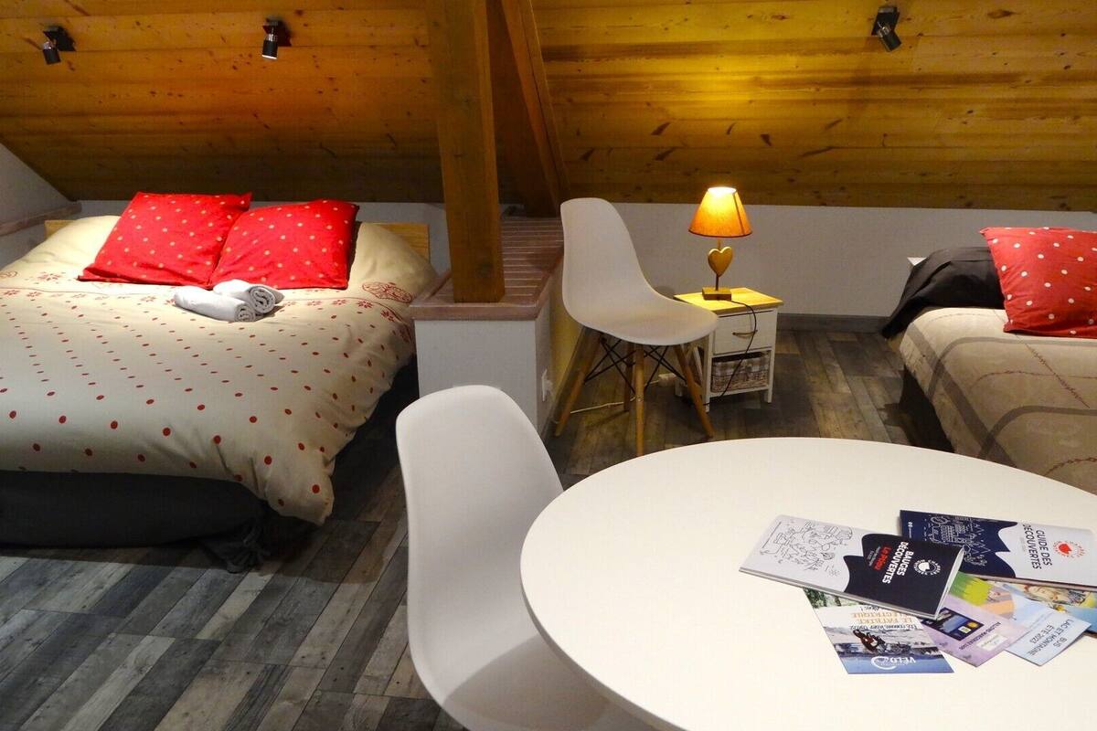 A cozy room with two beds, a small table, and a lamp.