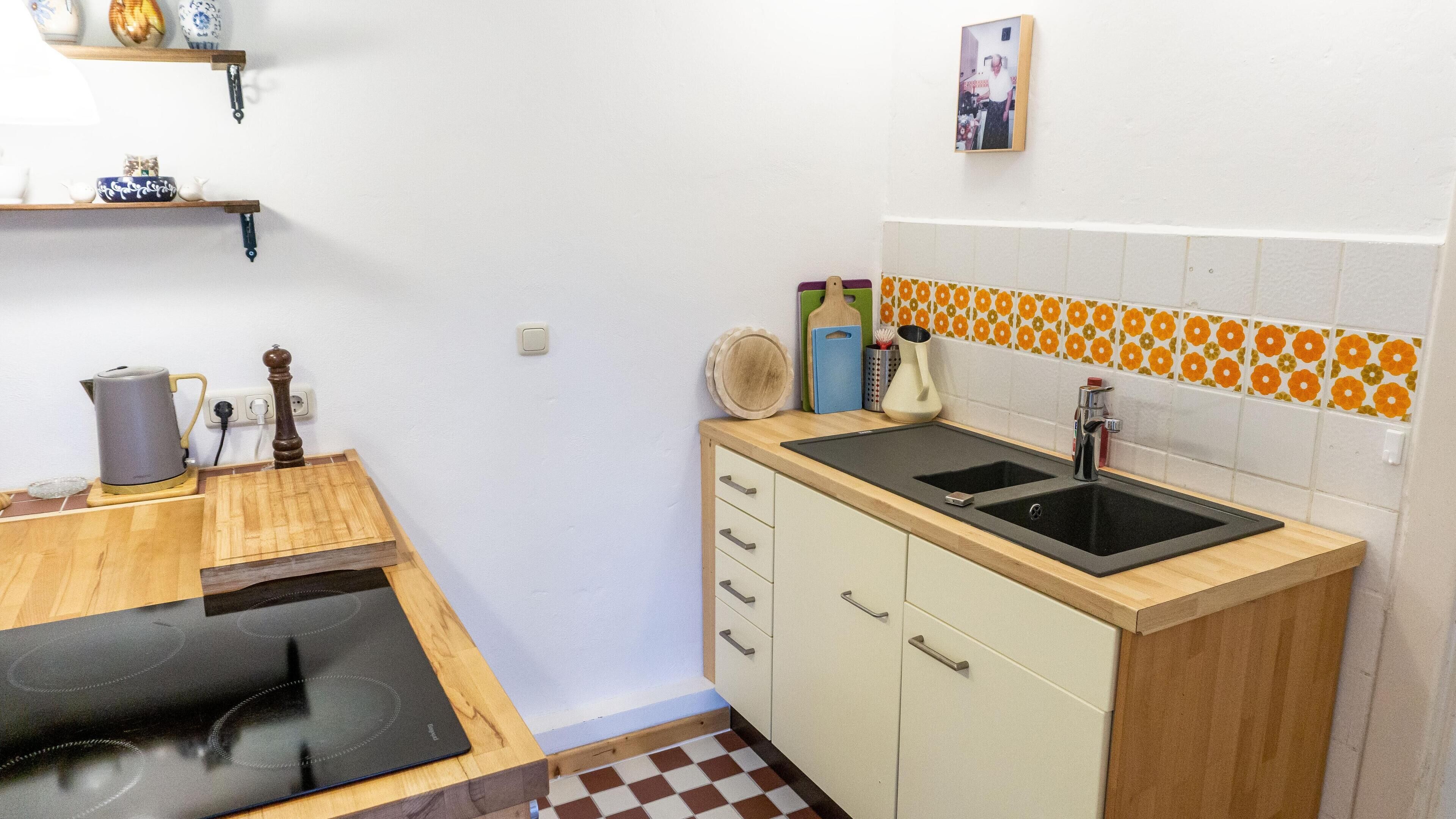 Una cocina compacta con encimera de madera, dos fregaderos, una estufa y un mueble pequeño.