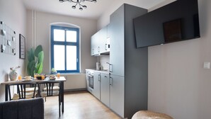 Eine moderne Küche mit grauen Schränken, einem Esstisch mit Stühlen und einem großen Fenster.