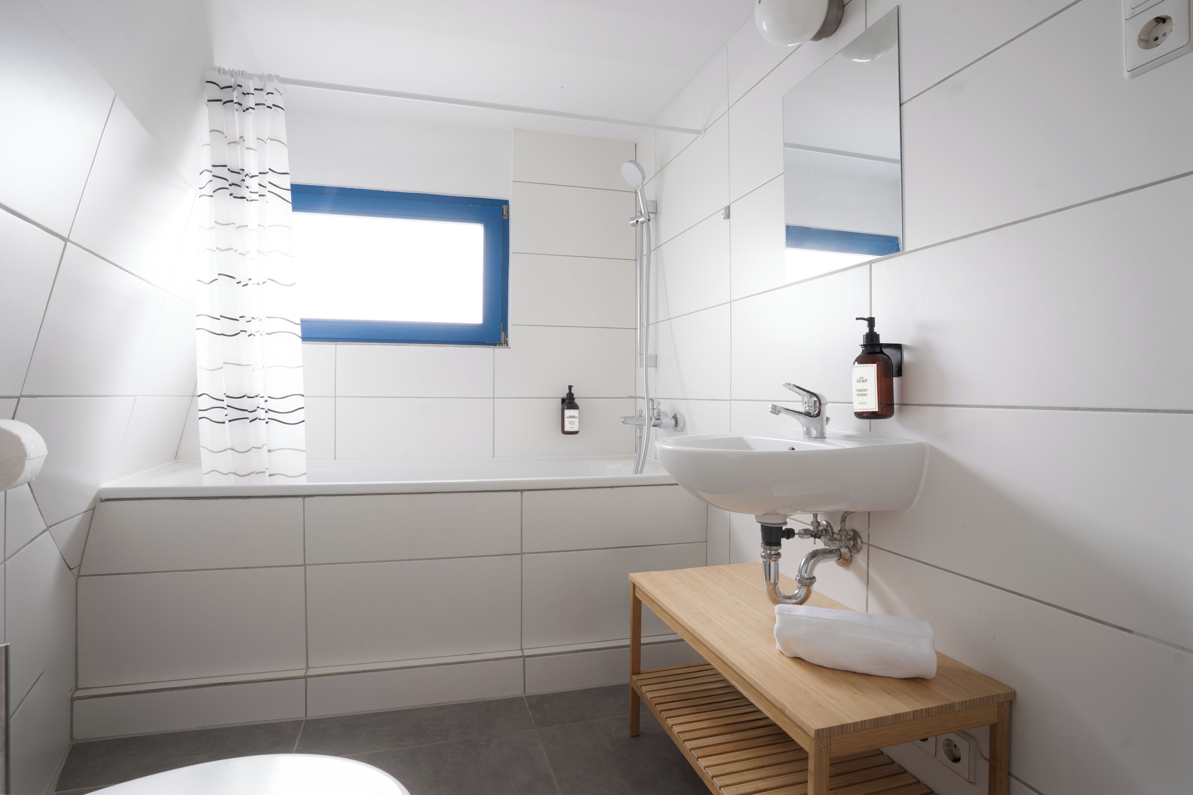 A modern bathroom with a bathtub, a sink, and a wooden vanity.