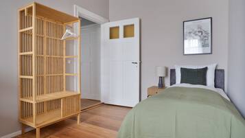 A bedroom with a bed, a nightstand, a wooden wardrobe, and a door.