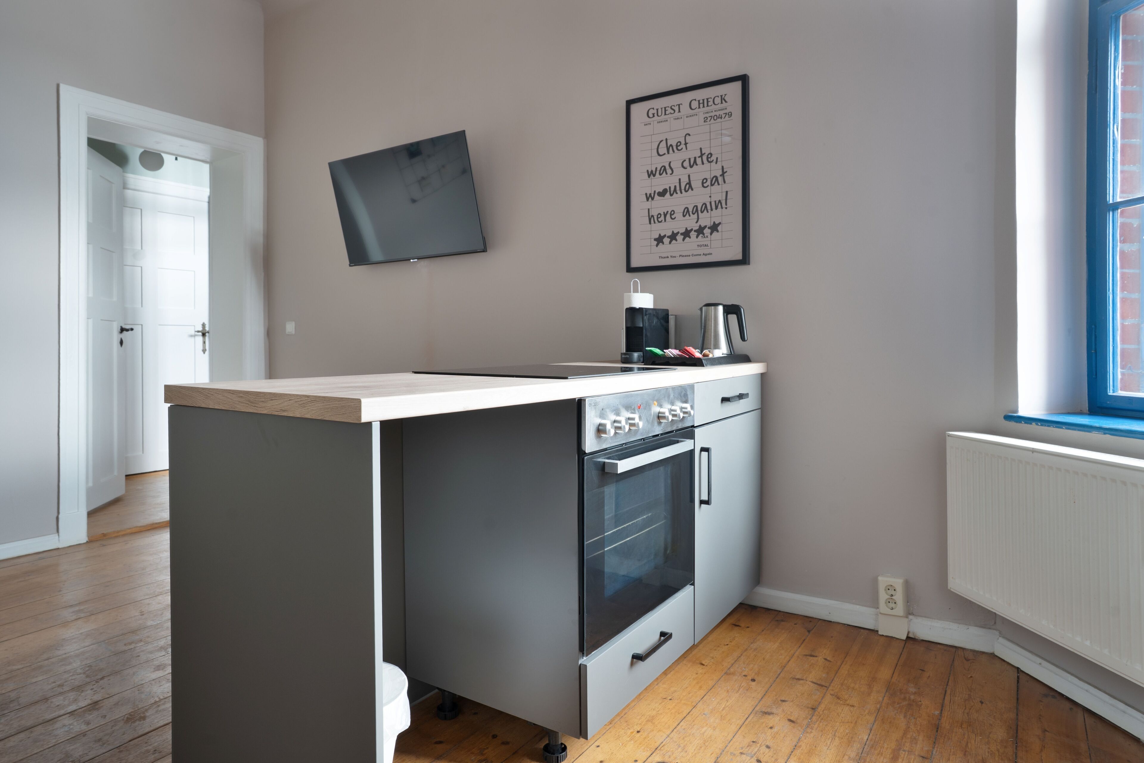 Una cucina moderna con forno integrato, un piano di lavoro e una TV a parete.