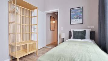 Une chambre d’hôtel avec un lit, une armoire en bois, un tableau encadré et une lampe.