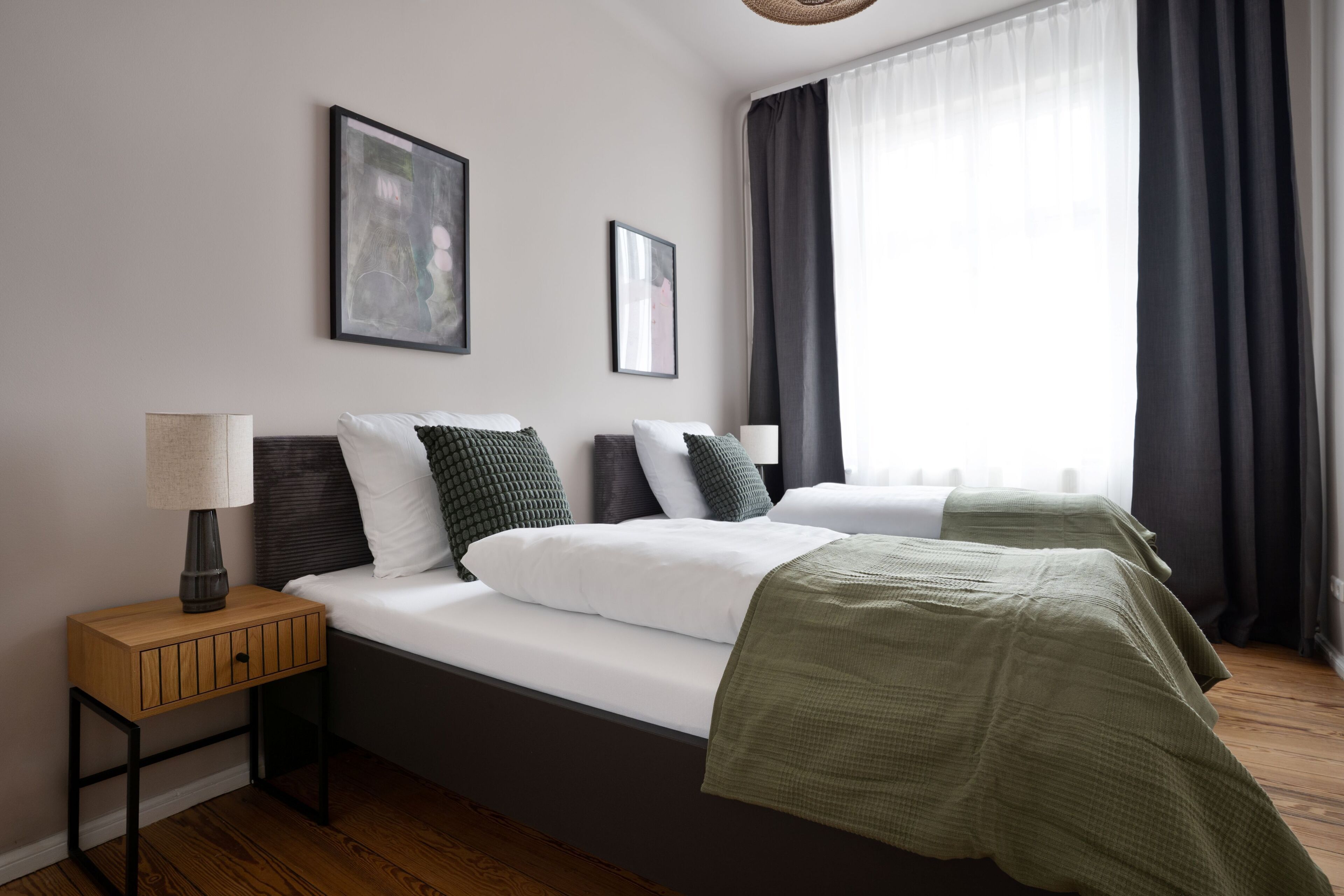 Ein modernes Hotelzimmer mit einem großen Bett, einem Nachttisch und einem Fenster mit Vorhängen.