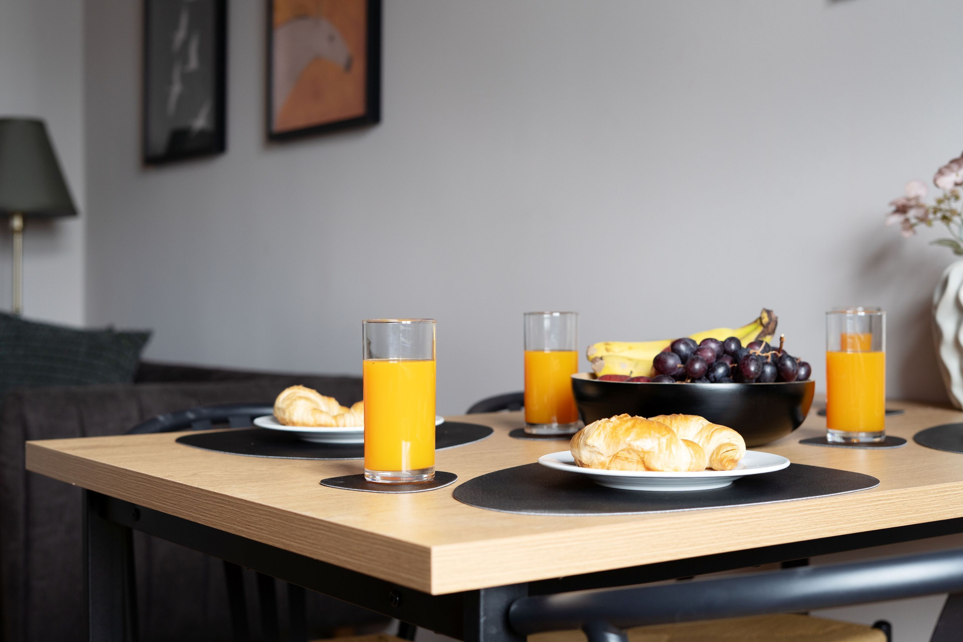 Ein Frühstückstisch mit Croissants, Obst und Orangensaft.