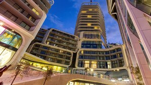 Un hotel moderno con una facciata curva, numerosi balconi e un ingresso in vetro ben visibile.