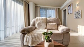Un soggiorno moderno con un divano beige, una coperta morbida e una pianta in vaso su un tavolino in legno.
