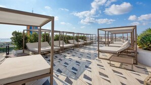 Una terrazza sul tetto con lettini prendisole e pavimento decorato, con vista sulla città.