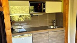 Eine kompakte Küche mit integriertem Mikrowellenherd, Spüle und kleinem Kühlschrank.