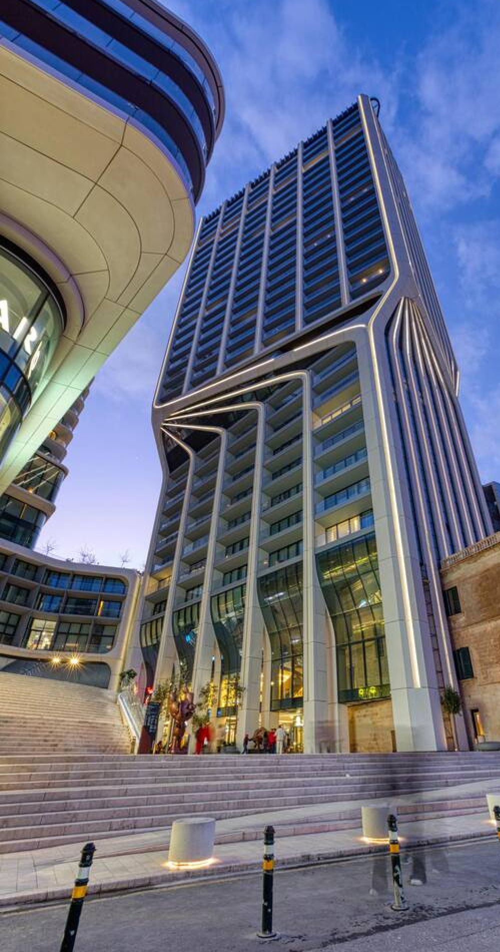 A modern high-rise building with a curved facade and multiple balconies.