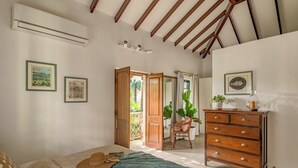 A bedroom with a bed, a dresser, and a balcony door. - Sanctuary by RÊVE Escapes (Siolim)