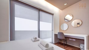 Habitación de hotel con cama, dos toallas, un escritorio, una silla y tres espejos redondos en la pared.