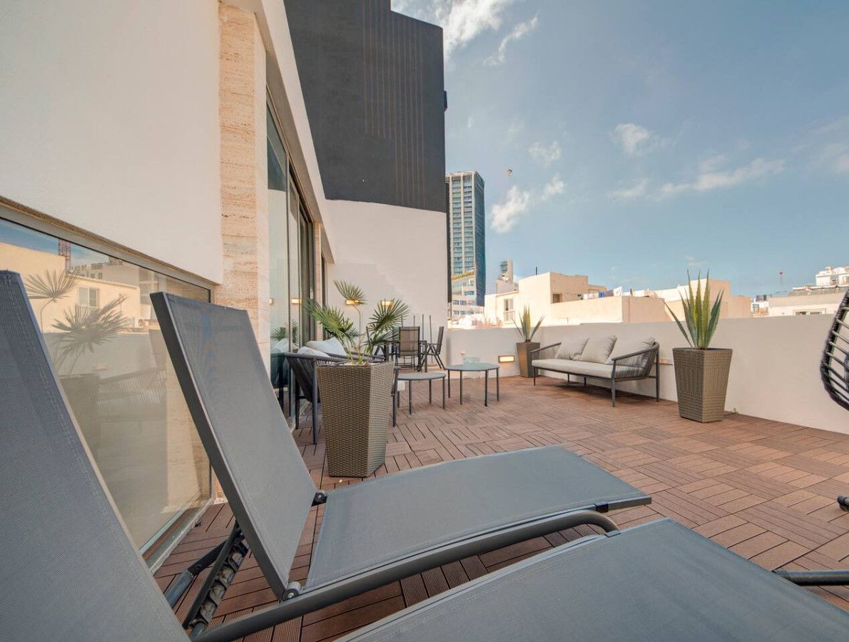 A rooftop terrace with outdoor seating, including chairs and a sofa, and a hanging chair.