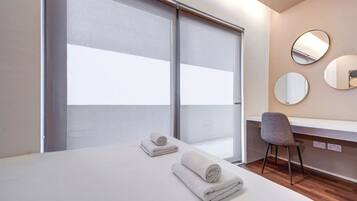 Une chambre d’hôtel avec un lit, deux serviettes, un bureau, une chaise et trois miroirs ronds accrochés au mur.