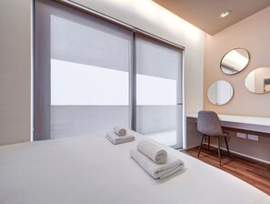 Habitación de hotel con cama, dos toallas, un escritorio, una silla y tres espejos redondos en la pared.
