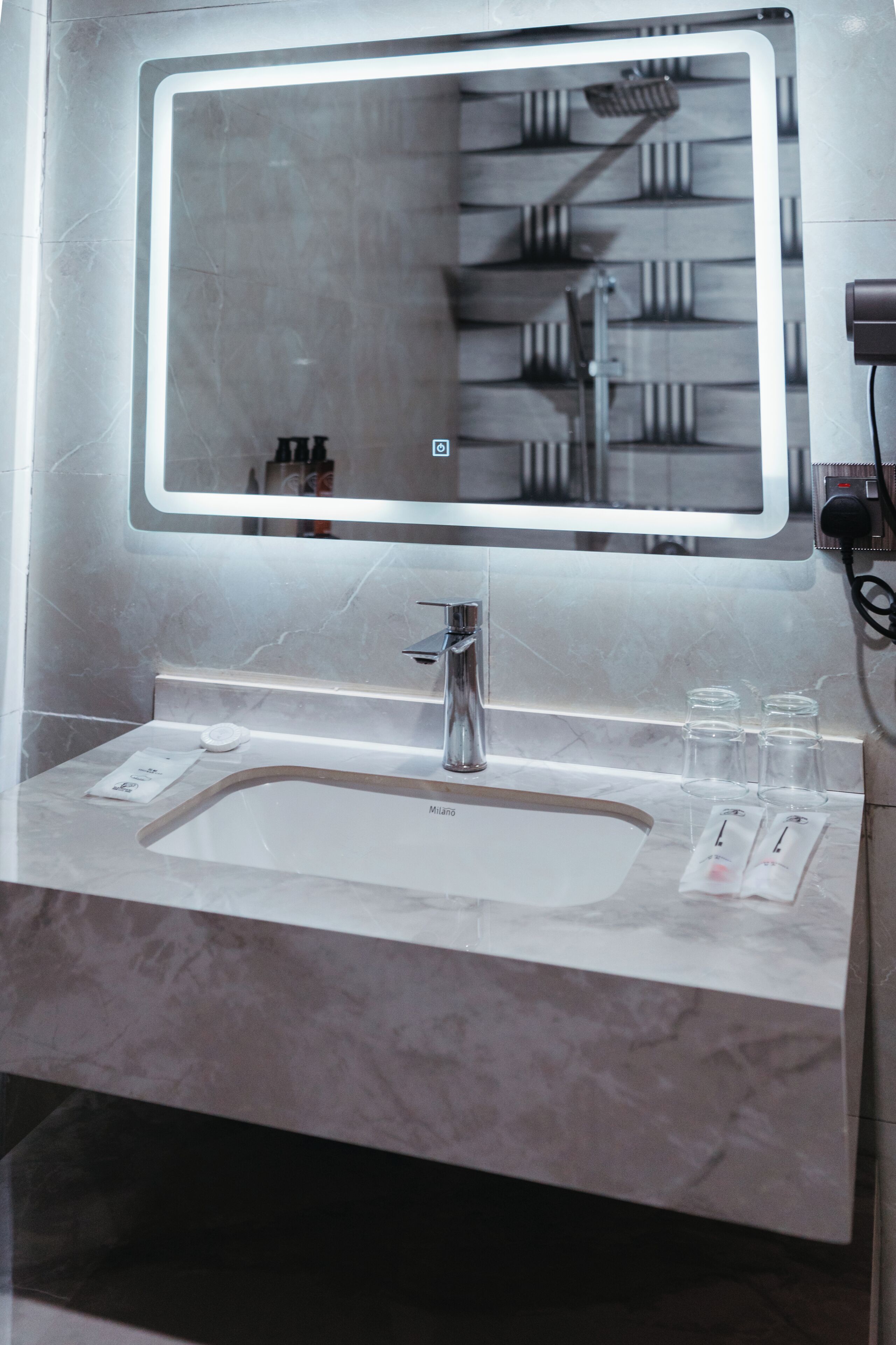 Een badkamer met een grote spiegel, een wastafel en een douche.
