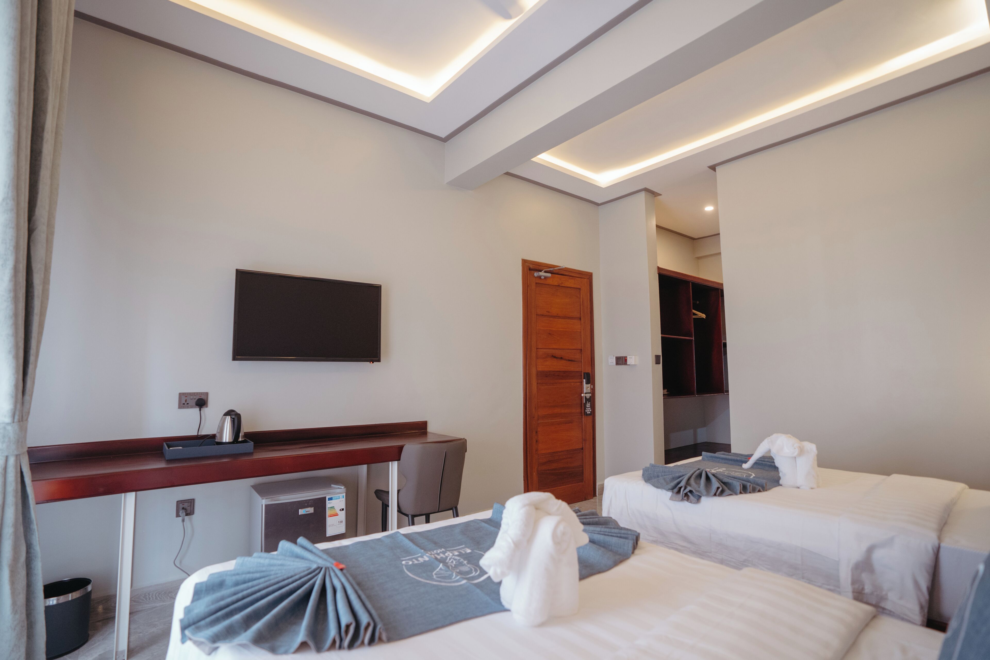 Une chambre d’hôtel équipée d’un bureau, de deux lits, d’une télévision et d’une armoire.