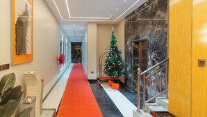 A hotel corridor with a red carpet, a Christmas tree, marble walls, and a staircase. - Elephantohotel (Zanzibar Town)